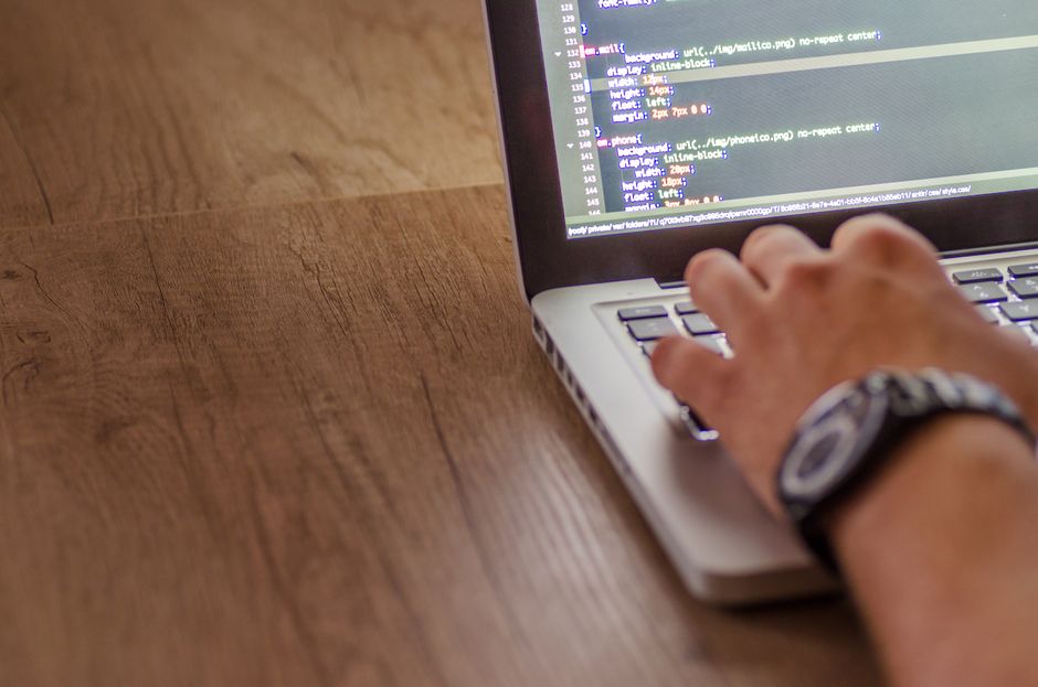 Close-up de uma pessoa codificando em um laptop, destacando conceitos de desenvolvimento web e programação.